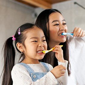 Mother and daughter brushing teeth